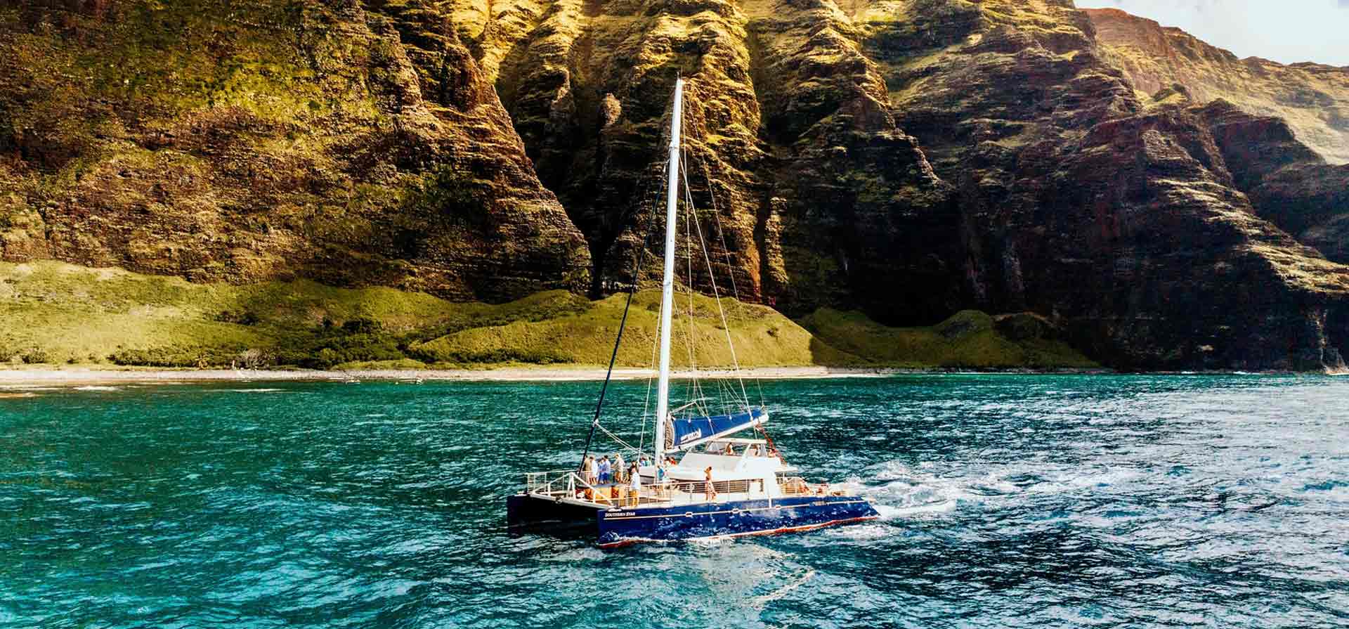 Kauai boat tour Napali Coast in the background, catamaran Kauai in the foreground.