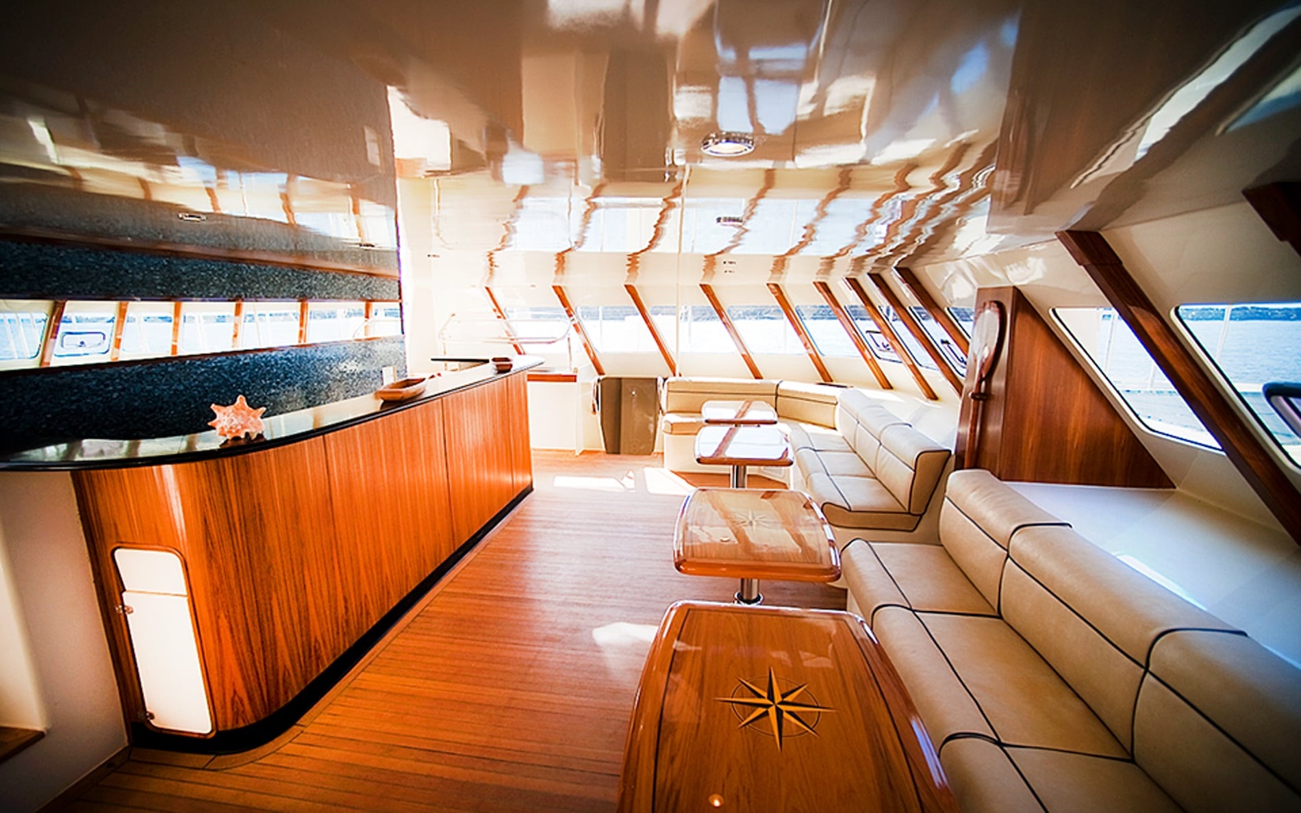 Elegant interior of Captain Andy's private charter yacht, featuring a spacious lounge with luxurious seating, wooden accents, and large windows offering panoramic ocean views
