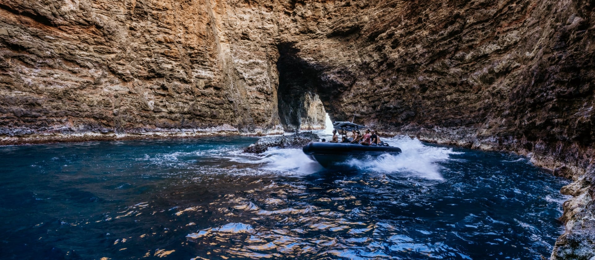 A 24'rigid-hull inflatable raft navigating through a dramatic sea cave.