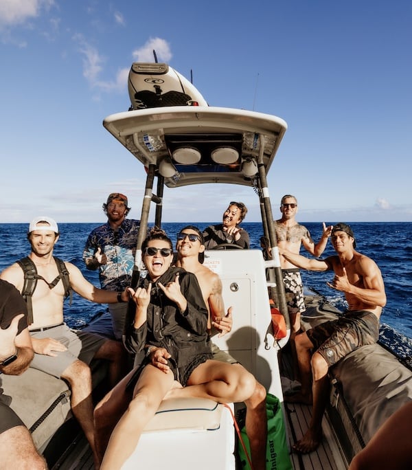 Group of friends on a Captain Andy's boat, making shaka signs and enjoying a sunny day on the ocean.