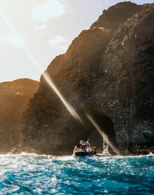 Boat entering a large sea cave along the rugged Na Pali Coast