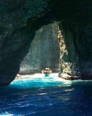 Boat entering a sunlit sea cave along the Na Pali Coast.